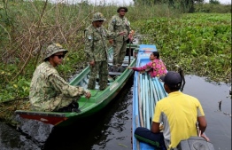 This photo taken on October 14, 2020 shows rangers stopping a fishing boat for questioning at a bird sanctuary and protected area by Prek Toal floating village in Battambang province. - More than a million people live on or around Tonle Sap lake, the world's largest inland fishery, but as a result of climate change and dams upstream on the Mekong, water levels are falling and fish stocks are dwindling. (Photo by TANG CHHIN Sothy / AFP) /