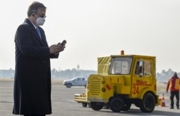 Mexican Foreign Minister Marcelo Ebrard uses his phone during the arrival of a plane of the international courier company DHL, carrying doses of the first batch of Pfizer vaccines which landed at Benito Juarez International Airport in Mexico City on December 23, 2020. - Mexico will begin Covid-19 immunizations on Thursday, a day after the country receives its first batch of Pfizer-BioNTech vaccines, Undersecretary of Health Hugo Lopez-Gatell said. (Photo by ALFREDO ESTRELLA / AFP)