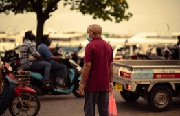 A man wearing a face mask, as a precautionary measure against COVID-19, waits to cross the street in the local market area of Male' City. PHOTO/PUBLICITY BUREAU