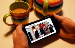 A man watches as Britain's Prime Minister Boris Johnson gives a televised message to the nation from 10 Downing Street in London, on his mobile phone in Liverpool, north west England on January 4, 2021, as the government announces a new lockdown for England because of an upturn in cases of the novel coronavirus Covid-19. (Photo by Paul ELLIS / AFP)
