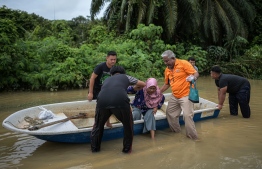 A woman disembarks from a boat after crossing a road submerged by floodwaters following heavy monsoon downpour in Lanchang in Malaysia’s Pahang state on January 6, 2021.
Mohd RASFAN / AFP