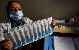 Indian doctor holds up samples of the AstraZeneca-Oxford developed Covid-19 vaccine. PHOTO: AFP