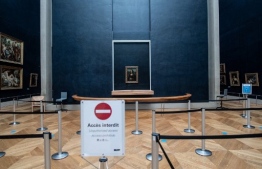 An information board is seen in front of the portrait of Lisa Gherardini, wife of Francesco del Giocondo, known as the Mona Lisa or La Gioconda (La Joconde in French), painted by Italian artsist Leonardo da Vinci, in the empty "Salle des Etats" of the Louvre Museum in Paris, on January 8, 2021. - The Louvre, which remains closed due to the sanitory situation, suffered the full impact of the Covid-19 pandemic in 2020, suffering a drop in attendance of 72% compared to 2019, and a loss of revenue of more than 90 million euros, the museum announced on January 8, 2021. (Photo by Martin BUREAU / AFP)