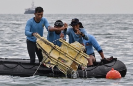 Indonesian Navy divers hold wreckage from Sriwijaya Air flight SJY182 during a search and rescue operation at sea near Lancang island on January 10, 2021, after the Boeing 737-500 crashed shortly after taking off from Jakarta airport on January 9. (Photo by ADEK BERRY / AFP)