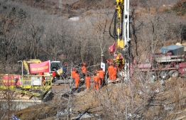 Members of a rescue team work at the site of a gold mine explosion where 22 miners are trapped underground in Qixia, in eastern China's Shandong province on January 18, 2021. - At least 12 gold miners trapped hundreds of metres underground in China for more than a week have sent up a note warning that they are injured, surrounded by water and urgently need medicine. (Photo by - / AFP) / 