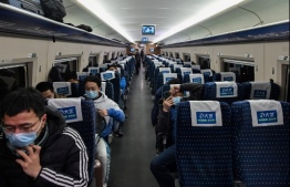This photo taken on January 18, 2021 shows passengers sitting on a train before it arrives at Wuhan train station in Wuhan in China's central Hubei province. - January 23 marks one year since the start of a 76-day lockdown of Wuhan, the central Chinese city where the coronavirus was first detected before sweeping across the world and killing more than two million people. (Photo by Hector RETAMAL / AFP)