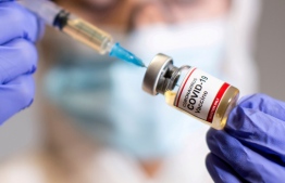 FILE PHOTO: A woman holds a small bottle labeled with a "Coronavirus COVID-19 Vaccine" sticker and a medical syringe in this illustration taken  October 30, 2020. REUTERS/Dado Ruvic/File Photo
