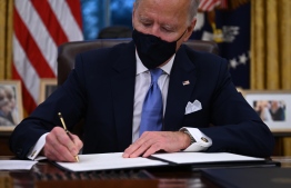 US President Joe Biden signs a series of orders in the Oval Office of the White House in Washington, DC, after being sworn in at the US Capitol on January 20, 2021. - US President Joe Biden signed a raft of executive orders to launch his administration, including a decision to rejoin the Paris climate accord. The orders were aimed at reversing decisions by his predecessor, reversing the process of leaving the World Health Organization, ending the ban on entries from mostly Muslim-majority countries, bolstering environmental protections and strengthening the fight against Covid-19. (Photo by Jim WATSON / AFP)