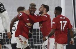 Manchester United's French midfielder Paul Pogba (L) celebrates with Manchester United's Portuguese midfielder Bruno Fernandes (2R) after scoring their second goal to take the lead 1-2 during the English Premier League football match between Fulham and Manchester United at Craven Cottage in London on January 20, 2021. (Photo by Adrian DENNIS / POOL / AFP) / RESTRICTED TO EDITORIAL USE. No use with unauthorized audio, video, data, fixture lists, club/league logos or 'live' services. Online in-match use limited to 120 images. An additional 40 images may be used in extra time. No video emulation. Social media in-match use limited to 120 images. An additional 40 images may be used in extra time. No use in betting publications, games or single club/league/player publications. / 