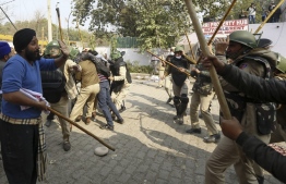 Police beat a a farmer during clashes as they continue to protest against the central government's recent agricultural reforms blocking a highway at the Delhi-Haryana state border in Singhu on January 29, 2021. (Photo by Arun KUMAR / AFP)