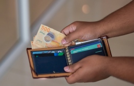 (FILE) Person taking Maldivian money out from a wallet: MMA believes foreign deposits have decreased as the cost of importing has increased -- Photo: Ahmed Awshan Ilyas