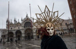 A Venetian artisan wearing a carnival mask and costume takes part in a demonstration of The Confederation of Venice Artisans (Confartigianato Venezia) at St. Mark's square in Venice on February 7, 2021, as the carnival is being cancelled due to the Covid-19 pandemic. - The trade association represents and protects more than 1,500 small businesses, not only craftsmen, in the Venice historical centre, the Islands and surrounding municipalities. (Photo by Marco Bertorello / AFP)