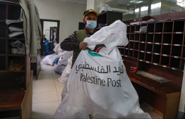 An employee of Palestine Post carries a bag of courrier at a post office in the West Bank town of Nablus on Febryary 7, 2021. The Palestinian Authority announced it would begin using its own postal codes, a gesture of sovereignty aimed at easing the delivery of parcels in their non-state entity. International mail sent to or from the occupied West Bank has to now transited either through Jordan or Israel. The PA said on February 7 that it had asked the Universal Postal Union to notify its member states of the coming into force of Palestinian postal codes.
JAAFAR ASHTIYEH / AFP