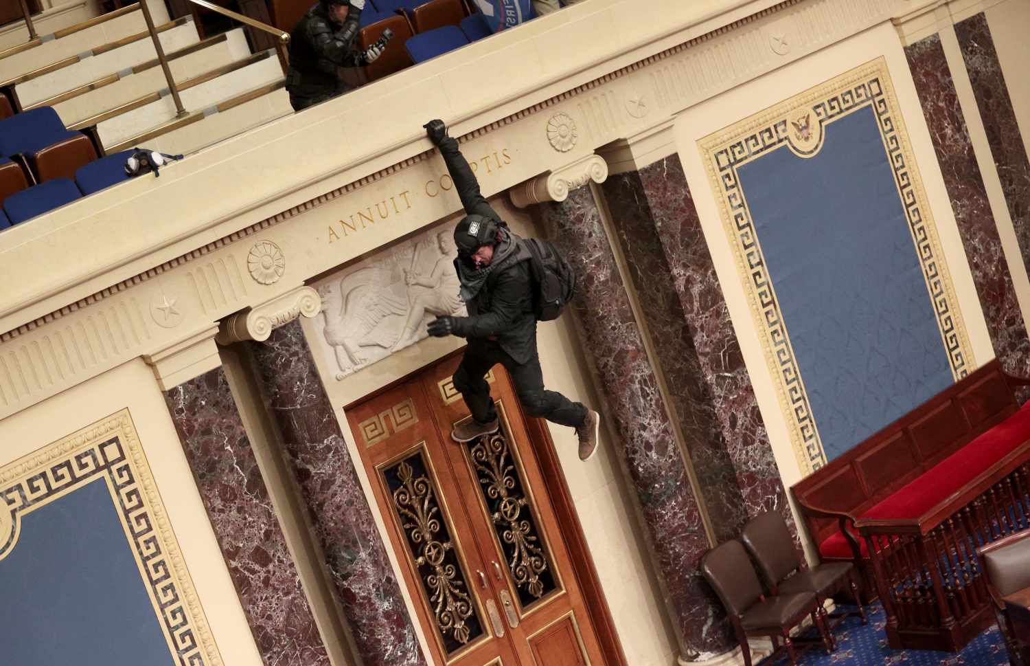 ޓްރަމްޕުގެ ސަޕޯޓަރުން ޖެނުއަރީ 6 ވަނަ ދުވަހު ސެނެޓުގެ ޗެމްބަރަށް ވަދެ ހިންގި ހަމަނުޖެހުމުގައި މީހަކު ސެނެޓުގެ ބެލްކަނީގައި އެލިގަނެގެން. --އޭއެފްޕީ ފައިލް ފޮޓޯ