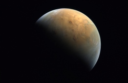 A handout picture provided on February 14, 2021 by the United Arab Emirates Space Agency (UAESA) taken by the Emirates eXploration Imager (EXI) after Mars Orbit Insertion (MOI) on board the First Emirates Mars Mission (EMM) from an altitude of 24,700 km above the Martian surface shows the Olympus Mons, the highest volcano on Mars, and the Tharsis Montes, three volcanoes named (top to bottom) Ascraeus Mons, Pavonis Mons and Arsia Mons.
United Arab Emirates Space Agency / AFP