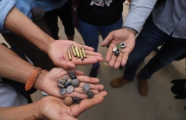 EDITORS NOTE:  / Protesters hold out bullet cartridges and ammunition for slingshots after security forces fired on demonstrators at a rally against the military coup in Mandalay on February 20, 2021. (Photo by str / AFP)