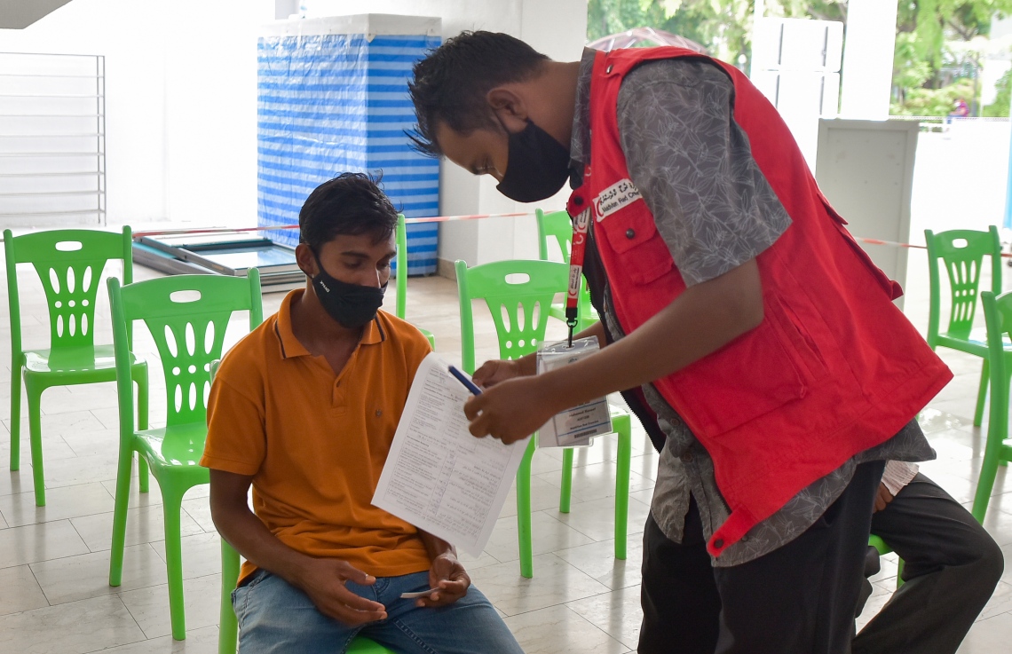 މާލެ: ފެބްރުއަރީ 25، 2021: ލިޔެކިޔުންނެތް ބިދޭސީއެއް ވެކްސިން ޖެހުމުގެ ކުރިން ފުރަންޖެހޭ މައުލޫމާތު ފޯމު ފުރަނީ.-- ފޮޓޯ: އަހުމަދު އަވްޝަން އިލްޔާސް /މިހާރު