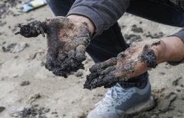 Hussein Hamza, a Lebanese environmental activist, shows off his hands covered with tar-soaked sands at the Tyre Nature Reserve, considered a destination for sea turtles to lay eggs, in Lebanon's southern coastal city of Tyre on February 22, 2021. - Israeli authorities on warned people to keep away from the country's Mediterranean shore to avoid a massive tar slick, as thousands of labourers and volunteers worked to clean contaminated beaches. Powerful winds and unusually high waves pummelled the southeastern Mediterranean coastline with tonnes of tar staining 160 kilometres (96 miles) of beaches along the coast from Gaza to Lebanon. (Photo by Mahmoud ZAYYAT / AFP)