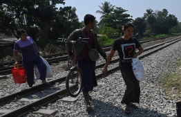 Railway staff carry their belonging as they flee over the train tracks after security forces arrived at Mahlwagone Railway Station to arrest workers involved in the Civil Disobedience Movement (CDM), in protest over the military coup, in Yangon on March 10, 2021.
STR / AFP