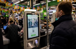 An X5 group representative demonstrates a facial recognition payment system at a  self-checkout machine in a Perekrestok supermarket in Moscow on March 9, 2021. - Russia's X5 group, the country's leading food retailer, announced on March 10 the launch of a facial recognition payment system, the latest expansion of a technology that has sparked privacy and security concerns. (Photo by Dimitar DILKOFF / AFP)