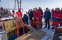 This handout picture released by the Institute for Nuclear Research of the Russian Academy of Sciences on March 13, 2021 shows scientists and officials watching the underwater neutrino telescope being immerged into the water of the Baikal lake. (Photo by Bair Shaibonov / Russian Institute for Nuclear Research / AFP) / 
