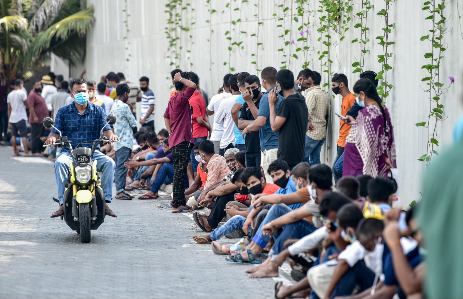 މާލެ- މާޗް 14، 2021: ކޮވިޑް ވެކްސިން ޖަހަން ސޯޝަލް ސެންޓަރު ބޭރުގައި ވަރަށް ގިނަ ބިދޭސީން ކިއުގައި ޖެހިގެން.-- ފޮޓޯ:ނިޝާން އަލީ/މިހާރު