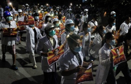 Medical staff and students take part in an early morning protest against the military coup and crackdown by security forces on demonstrations in Mandalay on March 21, 2021.
STR / AFP
