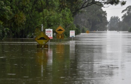 This picture shows road signs submerged in floodwaters at a residential area in the Windsor suburb of northwestern Sydney on March 23, 2021, after torrential downpours have lashed Australia's southeast for days. (Photo by Saeed KHAN / AFP)