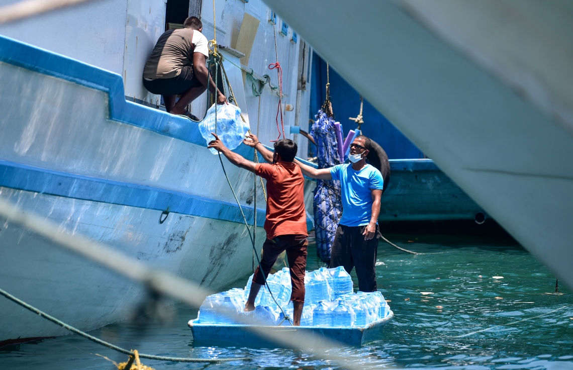 ރަށަކަށް ގެންދާ ފެންކޭސްތަކެއް މީހަކު ބޯޓަކަށް އަރުވަނީ: އަންނަ ހަފުތާގެ މެދުތެރޭގައި ރޯދަ މަސް ފަށާއިރު ވަރަށް ގިނަ ރަށްރަށަށް މިހާރު ވަނީ މުދާ ގެންދަން ފަށައިފައި -- ފޮޓޯ: އަހުމަދު އަވްޝަން/ މިހާރު