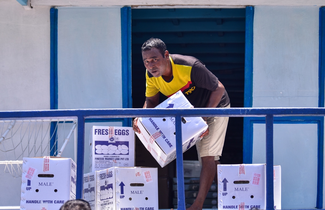 ރަށަކުން އައިސްފައި އޮތް މުދާ އުފުލާ ބޯއްޓަކަށް މީހަކު ބިސްކޭސް ތަކެއް އަރުވަނީ -- ފޮޓޯ: އަހުމަދު އަވްޝަން/ މިހާރު