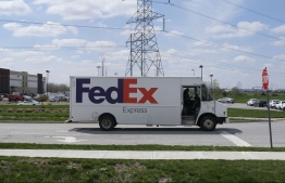 A FedEx truck drives past the site of a mass shooting at a FedEx facility in Indianapolis, Indiana on Friday, April 16, 2021. - A gunman has killed at least eight people at the facility before turning the gun on himself in the latest in a string of mass shootings in the country, authorities said. The incident came a week after President Joe Biden branded US gun violence an "epidemic" and an "international embarrassment" as he waded into the tense debate over gun control, a powerful political issue in the US. (Photo by Jeff Dean / AFP)