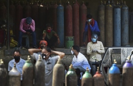 People wait to refill their medical oxygen cylinders for Covid-19 coronavirus patients at an oxygen refilling station in Allahabad on April 24, 2021. (Photo by Sanjay KANOJIA / AFP)