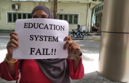 A parent holding a poster in front of the Education Ministry during protest --