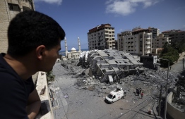 TOPSHOT - A Palestinian man looks at a destroyed building in Gaza City, following a series of Israeli airstrikes on the Hamas-controlled Gaza Strip early on May 12, 2021. - Palestinian militants in Gaza have fired more than 1,000 rockets towards Israel, when hostilities between the rivals escalated dramatically following days of unrest in Jerusalem, the Israeli army said. (Photo by MOHAMMED ABED / AFP)