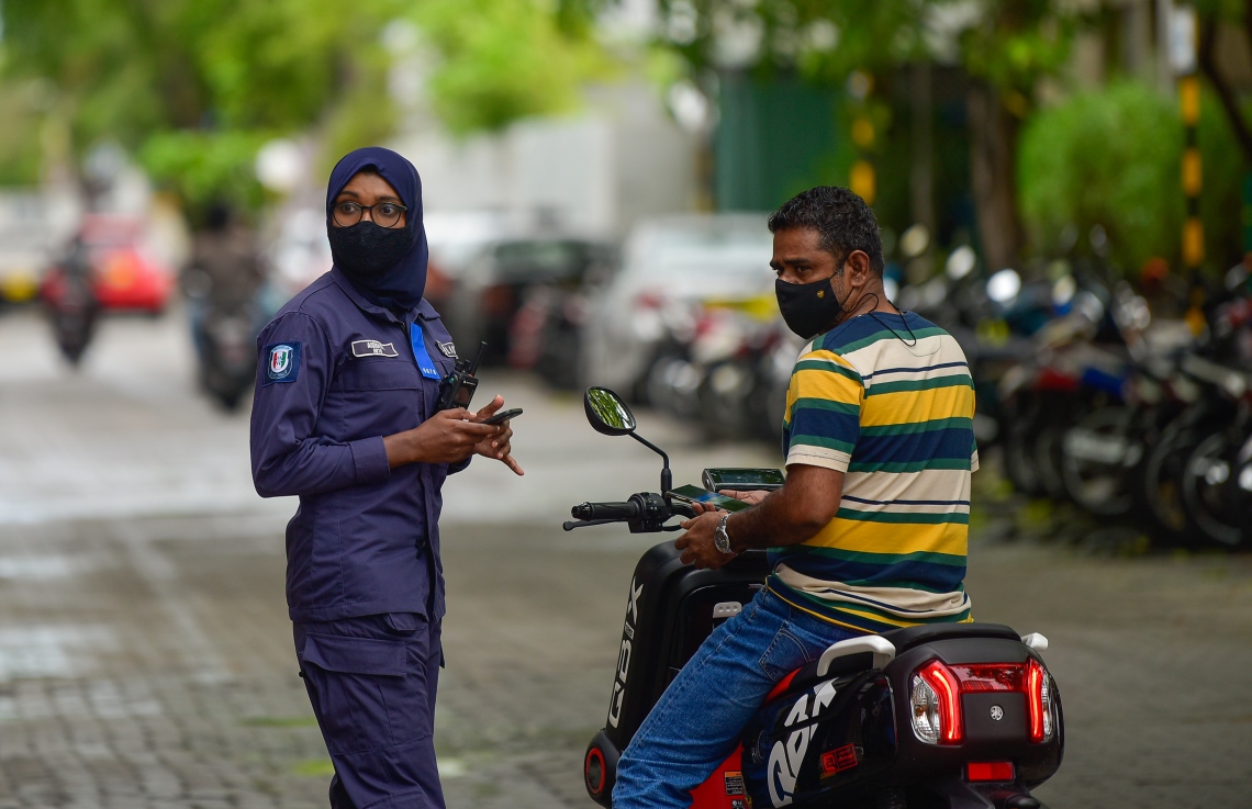 މާލެ- މެއި 13، 2021: ކާފިއު ހިންގާފައި އޮތް އިރު އަންހެން ފުލުހަކު އިއްޔެ މަގުމަތީގައި މީހަކާ ސުވާލުކުރަނީ: މި ކާފިއު ހަފުތާއަކަށް ދެމިގެންދާނެ، ސަރުކާރުގެެ ބޭނުމަކީ މިހާރު އޮތް ކޮވިޑްގެ ރާޅުގެ ބާރު ދަށްކޮށްލުންް-- ފޮޓޯ:އަހުމަދު އަވްޝަން އިލްޔާސް/ މިހާރު