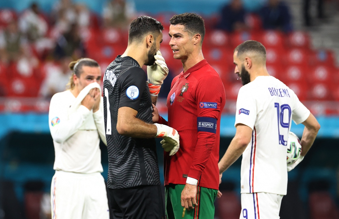 ބުޑަޕެސްޓް: ޖޫން 24، 2021: ޔޫރޯ 2020ގެ ގްރޫޕް އީގެ ފްރާންސް އާއި ޕޯޗުގަލް ބައްދަލުކުރި މެޗުގައި ޕޯޗުގަލްގެ ފޯވާޑް ކްރިސްޓިއާނޯ ރޮނާލްޑޯ(ކ) ޕޯޗުގަލްގެ ގޯލްކީޕަރާ ވާހަކަ ދައްކަނީ: ފްރާންސްގެ މައްޗަށް 2-2 ގެ ނަތީޖާ އަކުން އެއްވަރުކޮށް ޕޯޗްގަލް ވަނީ ދެވަނަ ބުރަށް ދަތުރު ކޮށްފައި.-- ފޮޓޯ: އޭއެފްޕީ