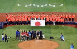 Gold medal winning Japan's baseball players (rear) and Japan's baseball officials (front) pose on the podium during the medal presentation ceremony for the baseball competition in the Tokyo 2020 Olympic Games at Yokohama Baseball Stadium in Yokohama, Japan, on August 7, 2021 -- Photo STR / JIJI PRESS / AFP