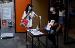 A woman gets her temperature checked at the entrance of a restaurant in Beijing on August 10, 2021 -- Photo: WANG Zhao/ AFP