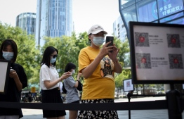 People use their mobile phones to scan a QR health code as a preventive measure against the Covid-19 coronavirus at the entrance of a business district in Beijing on August 10, 2021 -- Photo: WANG Zhao/ AFP