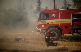 A firefighter from Slovakia cools himself down during a wildfire near in the village of Avgaria on Evia (Euboea) island, on August 10, 2021. - Nearly 900 firefighters, reinforced overnight with fresh arrivals from abroad, were deployed on the country's second largest island as major towns and resorts remained under threat from a fire that has been burning for eight days. (Photo by ANGELOS TZORTZINIS / AFP)