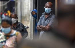 Residents watch army health officials (not pictured) conducting the Covid-19 coronavirus mobile vaccination drive in a locality in Colombo on August 12, 2021. (Photo by Ishara S. KODIKARA / AFP)