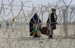 Afghan nationals walk along a fenced corridor after crossing into Pakistan through the Pakistan-Afghanistan border crossing point in Chaman on August 28, 2021 following the Taliban's military takeover of Afghanistan. -- Photo:  AFP