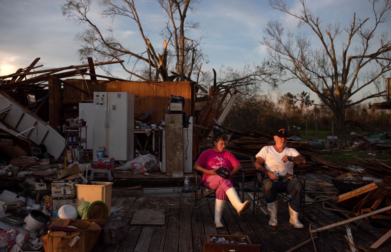 އައިޑާ ތޫފާންގެ ސަބަބުން ހަލާކުވެފައިވާ ގެއެއްގެ ބޭރުގައި، އެ ގޭގައި ދިރިއުޅޭ ދެމަފިރިން މަޑުކޮށްލައިގެން. --އޭއެފްޕީ