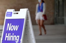 (FILES) In this file photo a woman walks by a "Now Hiring" sign outside a store on August 16, 2021 in Arlington, Virginia -- Photo: Olivier Douliery/ AFP