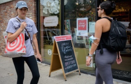 (FILES) In this file photo taken on August 20, 2021 People walk past a "We're hiring"' sign posted at a store in New York City. -- Photo: Angela Weiss / AFP