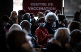 (FILES) In this file photo taken on April 3, 2021 people sit in a waiting area before being vaccinated against Covid-19 on the opening day of a mass vaccination centre set up in the OL Group's Groupama Stadium, in Decines-Charpieu. - A woman was found dead of natural causes in the apartment she lives with her children. -- Photo: Jean-Philippe Ksiazek / POOL / AFP