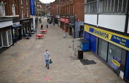 (FILES) In this file photo taken on June 16, 2021 a pedestrian wearing a face covering due to Covid-19 walks past closed-down shops in Blackburn, north west England on June 16, 2021. - The UK government's furlough scheme that has kept millions of private-sector workers in jobs during the pandemic ends on September 30, 2021, triggering predictions of a jump in unemployment affecting the most vulnerable. -- Photo by Oli Scarff/ AFP