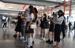 (FILES) This file photo taken on August 25, 2021 shows fans holding cameras waiting for celebrities at Beijing’s Capital Airport in Beijing. State regulations banned online celebrity rankings, fundraising and other tools used by China's "chaotic" online fandoms to get their idols trending, in a country where young people have few other means of influencing public life. -- Photo: Jade Gao/ AFP