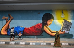 A family walks past a mural painted on the side of a bridge in New Delhi on October 2, 2021: New Delhi Chief Minister Arvind Kejriwal has said major coal-fired station in Delhi have barely a day's stock left -- Photo: Sajjad Hussain/ AFP