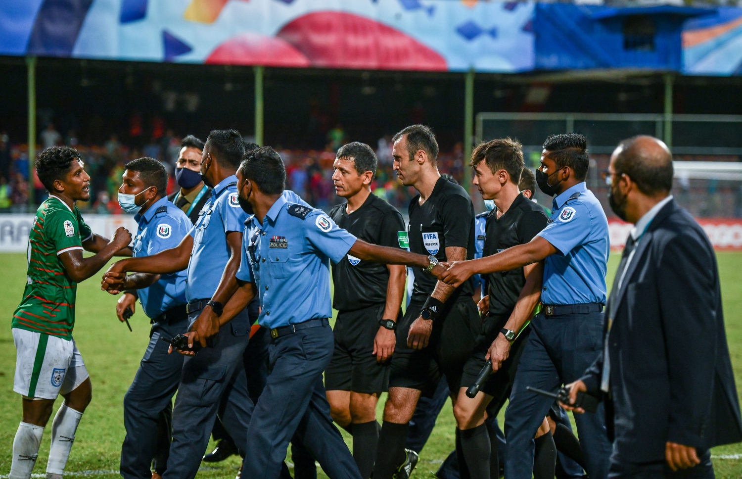 މެޗަށް ފަހު މެޗުގެ އޮފިޝަލުންނަށް ފުލުުން ހިމާޔަތް ދެނީ. ބަންގްލަދޭޝްގެ ކުޅުންތެރިން ވަނީ ރެފްރީގެ ނިންމުމާމެދުވަރަށް ބޮޑަށް ހިތްހަމަނުޖެހުން ފާޅުކޮށްފައި --- ފޮޓޯ: ނިޝާން އަލީ | މިހާރު